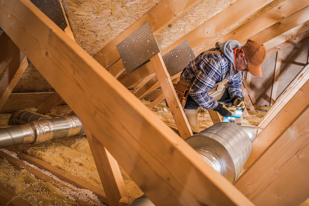 Worker installing HVAC ductwork in attic