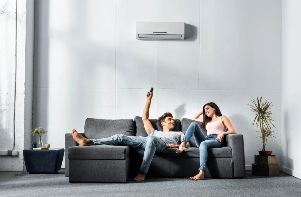 Couple relaxing on sofa under air conditioner.
