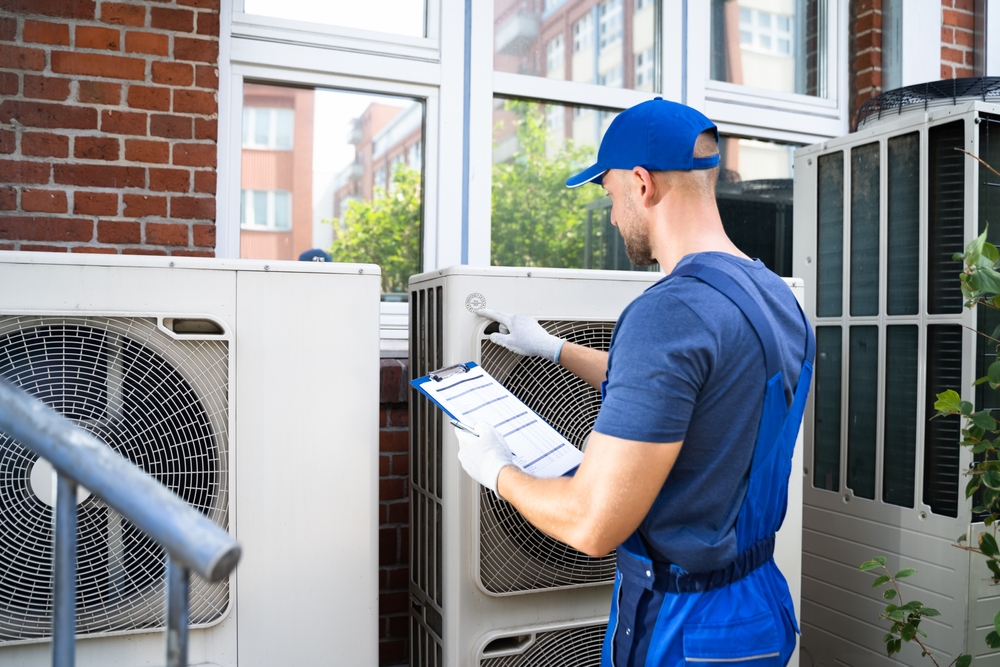 Technician inspecting outdoor air conditioning unit.